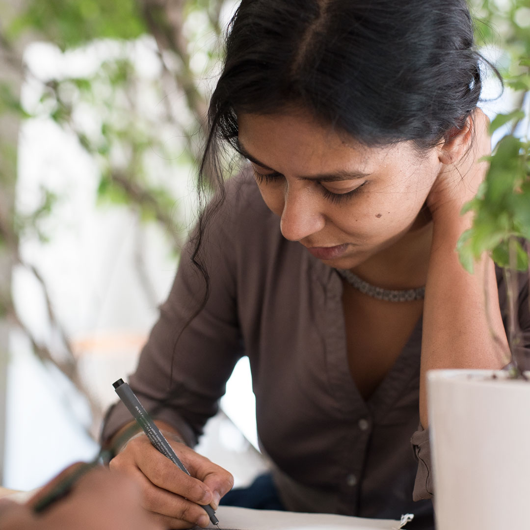 Ayeshe inking a drawing.